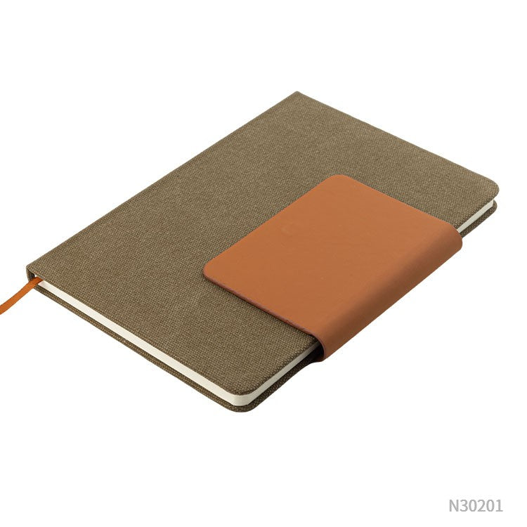 Cuaderno A5 en tela ecológica detalle en PU eco cuero. Puede personalizarse, para regalos promocionales, con un logotipo impreso en 1 tinta o con grabado láser.