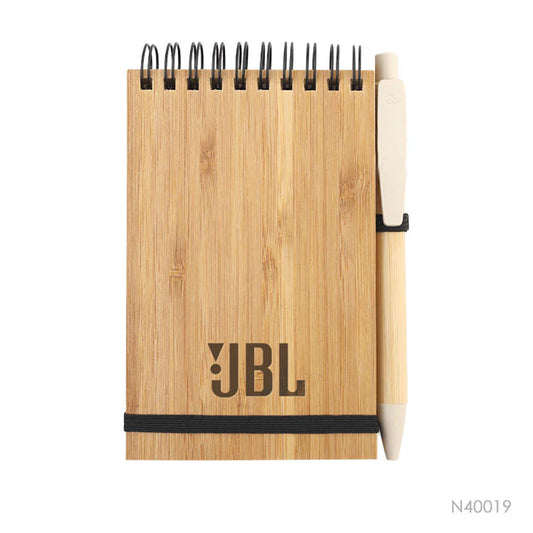Lapicera y libreta con tapa de bambú y hojas recicladas. La libreta tiene un logo