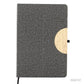Cuaderno porta celular de tela R-PET y detalle en bambú, disponible en colores gris o negro. Logotipo en grabado láser en la tapa.